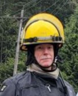 Brian Owen in his firefighter gear with a forest in the background